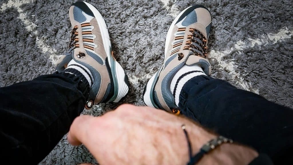 A person's feet wearing comfortable, cushioned running shoes with striped socks.