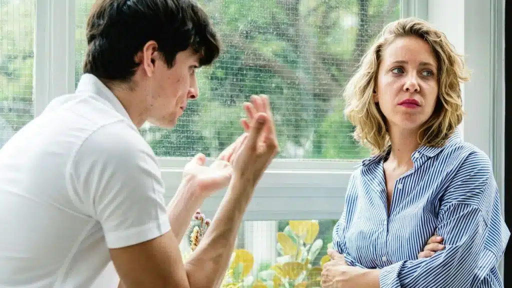 A distressed man argues while a woman with arms crossed looks away.