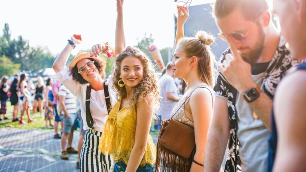 A group of young friends enjoying themselves at an outdoor music festival.