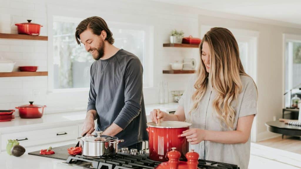 A happy couple working together to cook a meal in a bright kitchen.