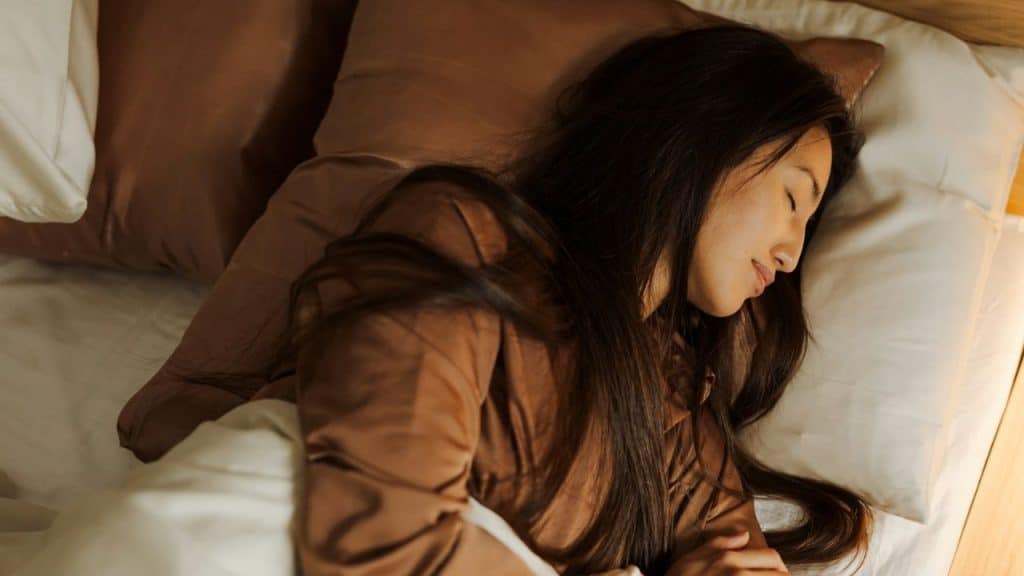A woman with long, dark hair is sleeping in bed.