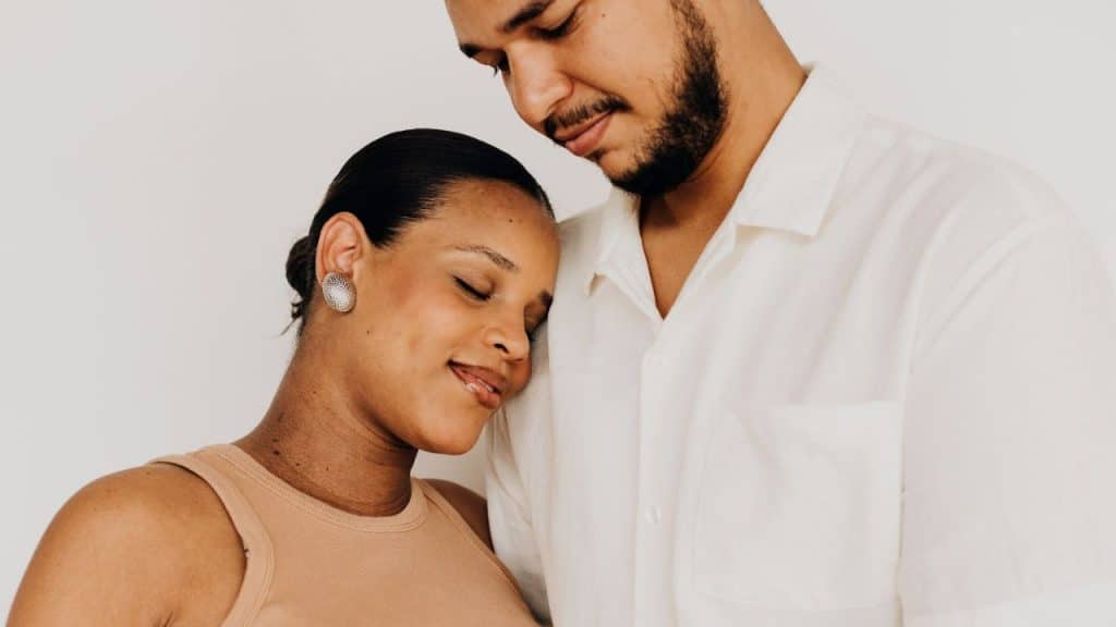 Woman resting her head on a man's shoulder, smiling with her eyes closed.