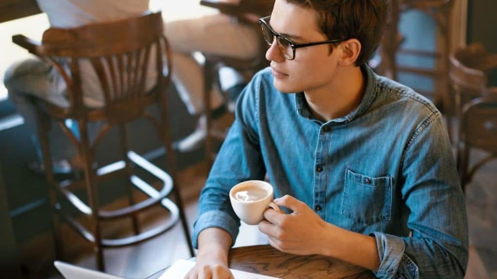 A man sitting thoughtfully while holding a coffee cup