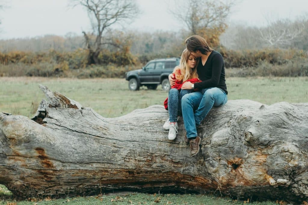 A man and woman sitting at the log