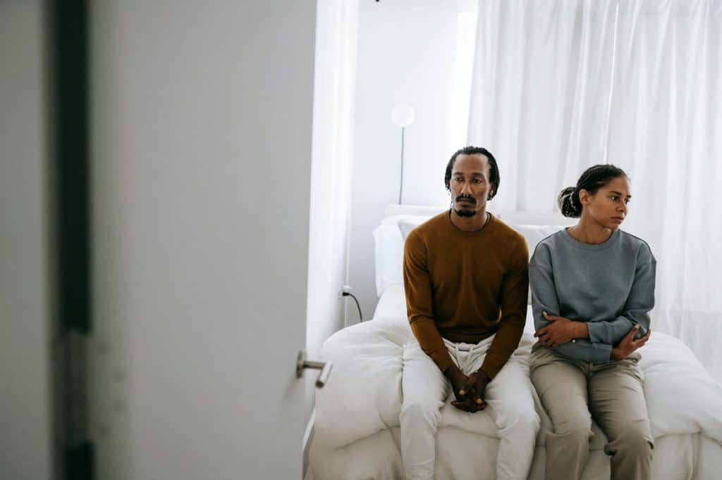 A man and woman sitting at the bed