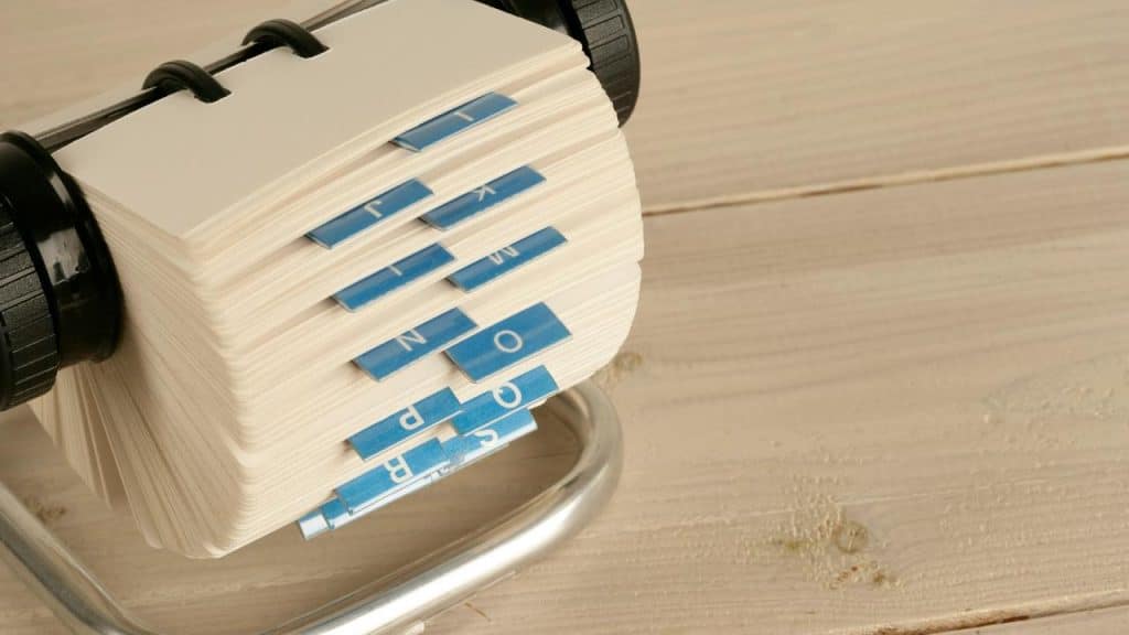 A rotary card file with alphabetical tabs on a wooden table.