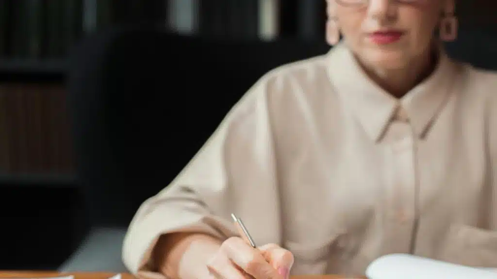 A woman writing in a notebook at a desk.
