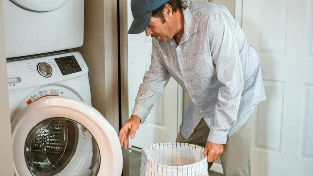 A man loading clothes into a front-loading washing machine.