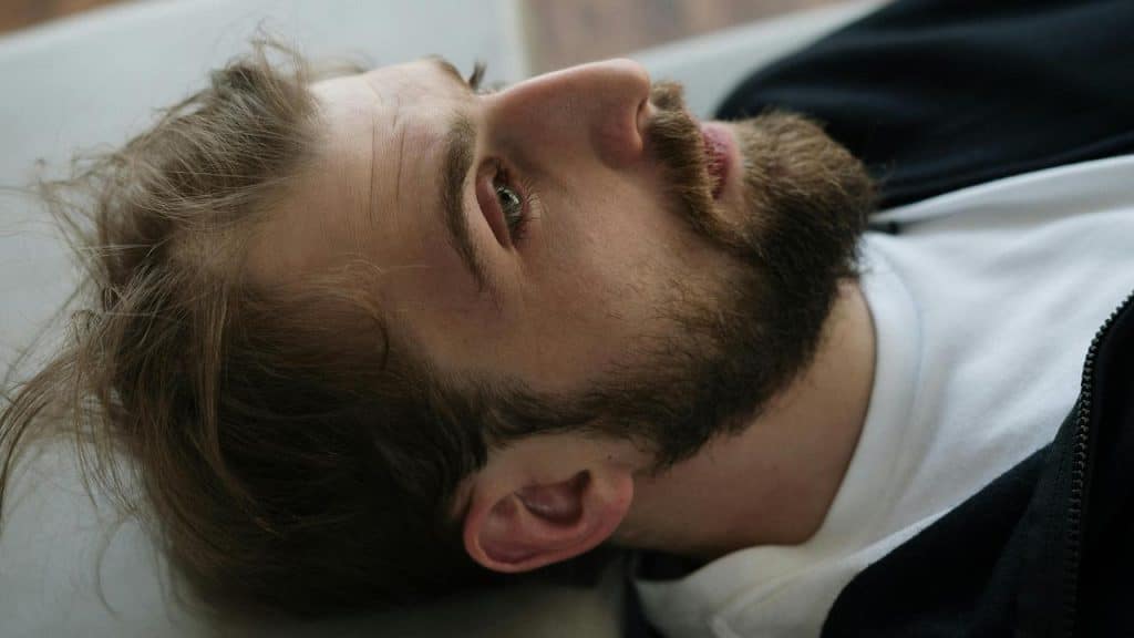 A man lying down on a couch staring off to the side.