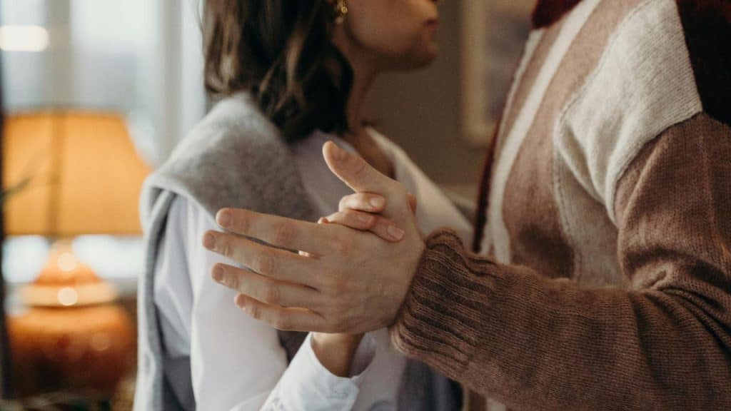 A couple standing close together holding hands as if dancing.