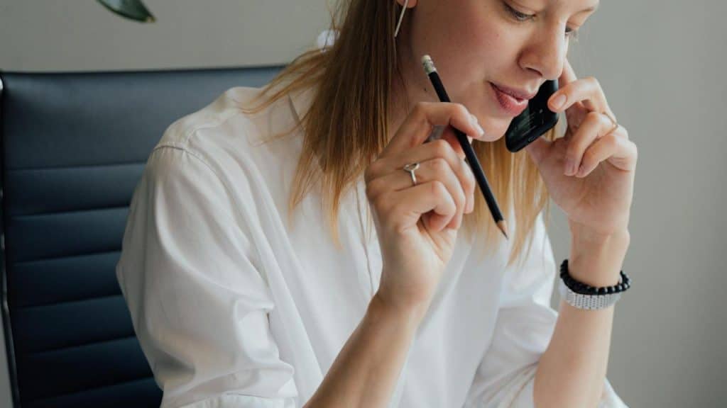 A woman talking on the phone while holding a pencil.