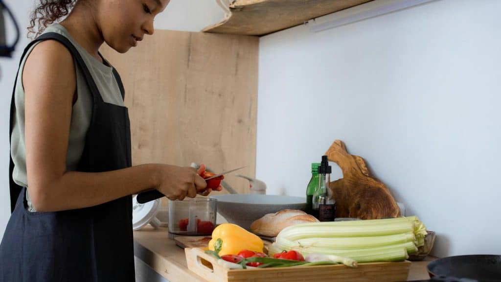 A woman chopping vegetables in the kitchen.