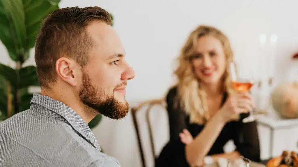A man sitting at a table with a woman holding a glass of wine.