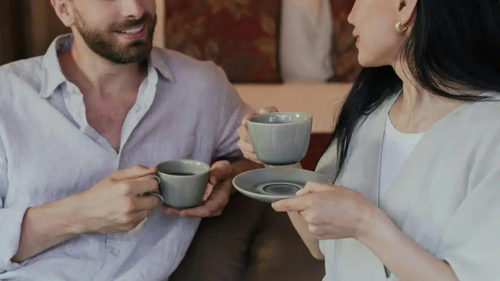 A couple sitting together holding cups of coffee.