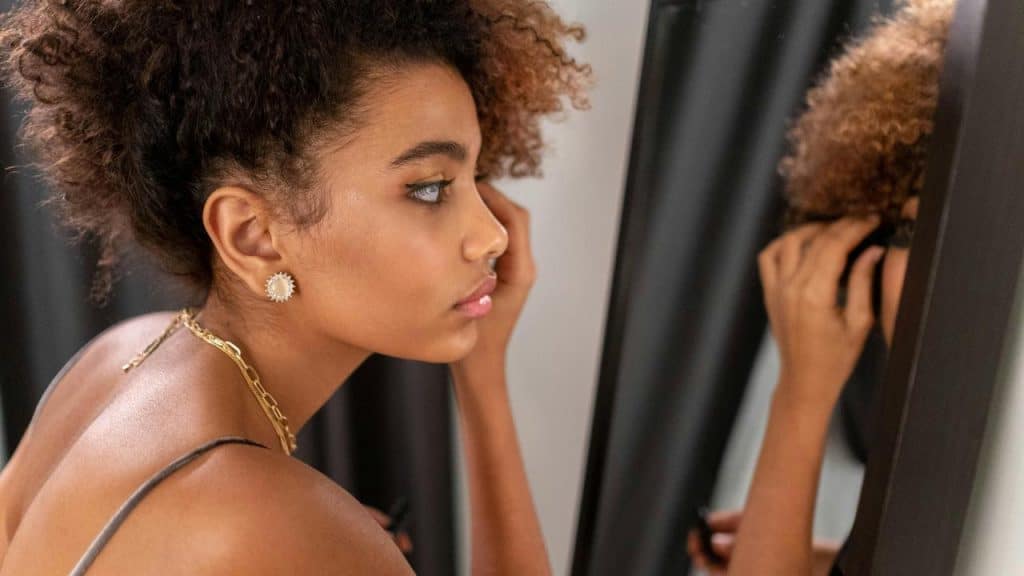 A woman applying mascara while looking in a mirror.