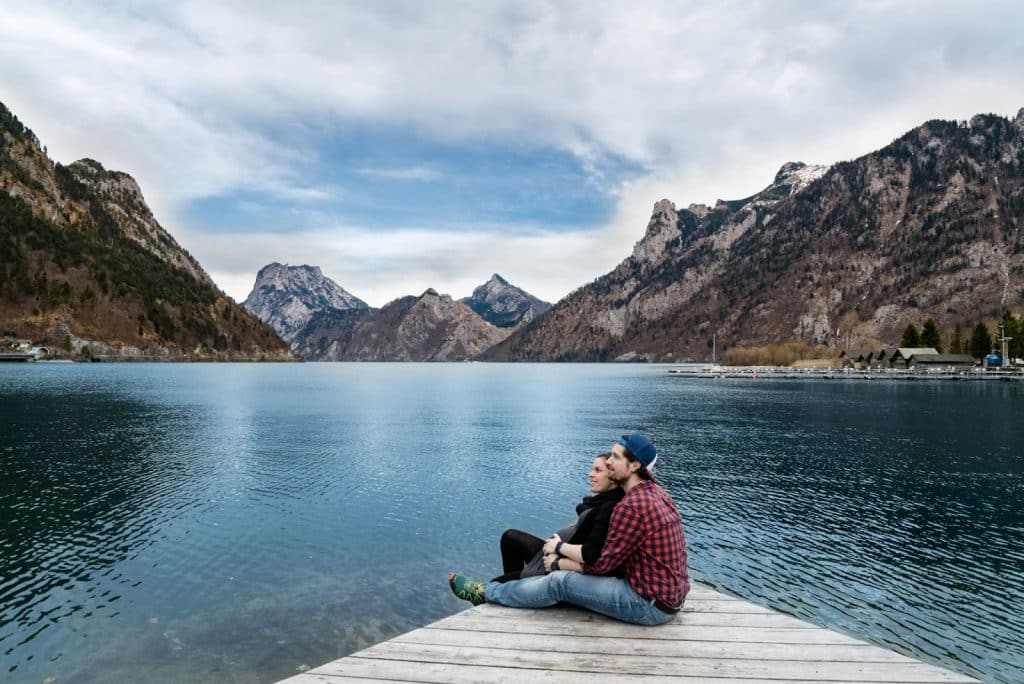 A man and woman sitting on a wooden dock