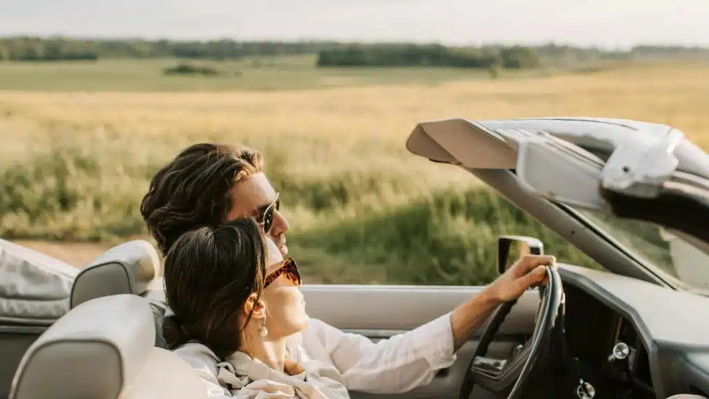 A couple enjoying a drive in a convertible through the countryside.