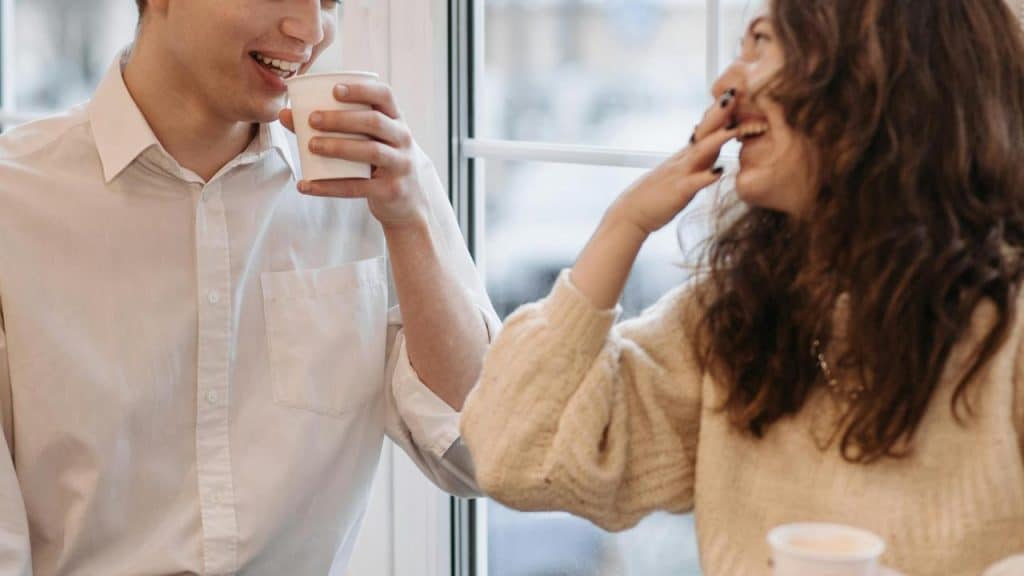 A man and woman laughing while having coffee together.