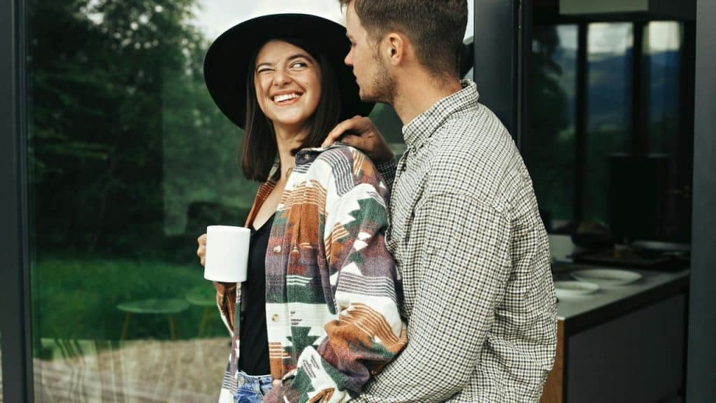A woman holding a mug smiling at a man standing close to her.
