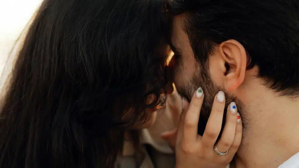 A woman gently holding a man’s face while leaning in close.