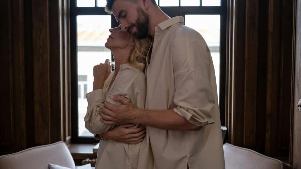 A couple embracing near a window.