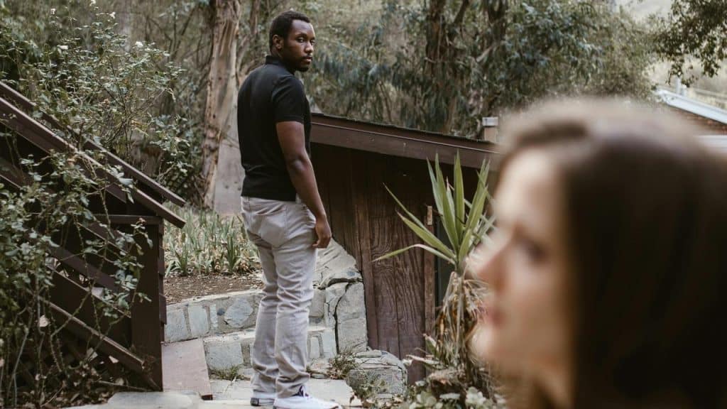 A man standing on outdoor steps looking back at a woman in the foreground.