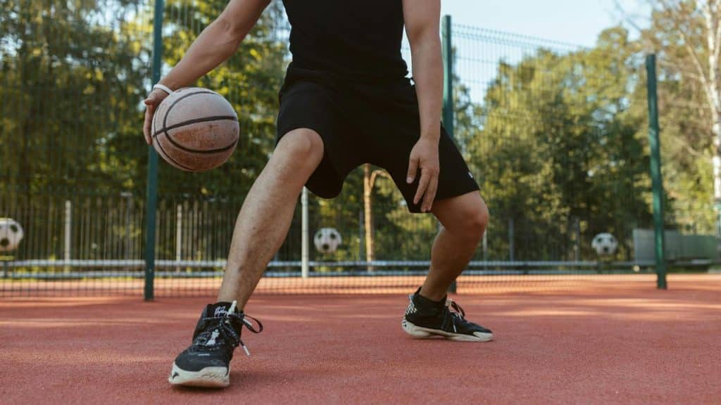A person dribbling a basketball on an outdoor court.