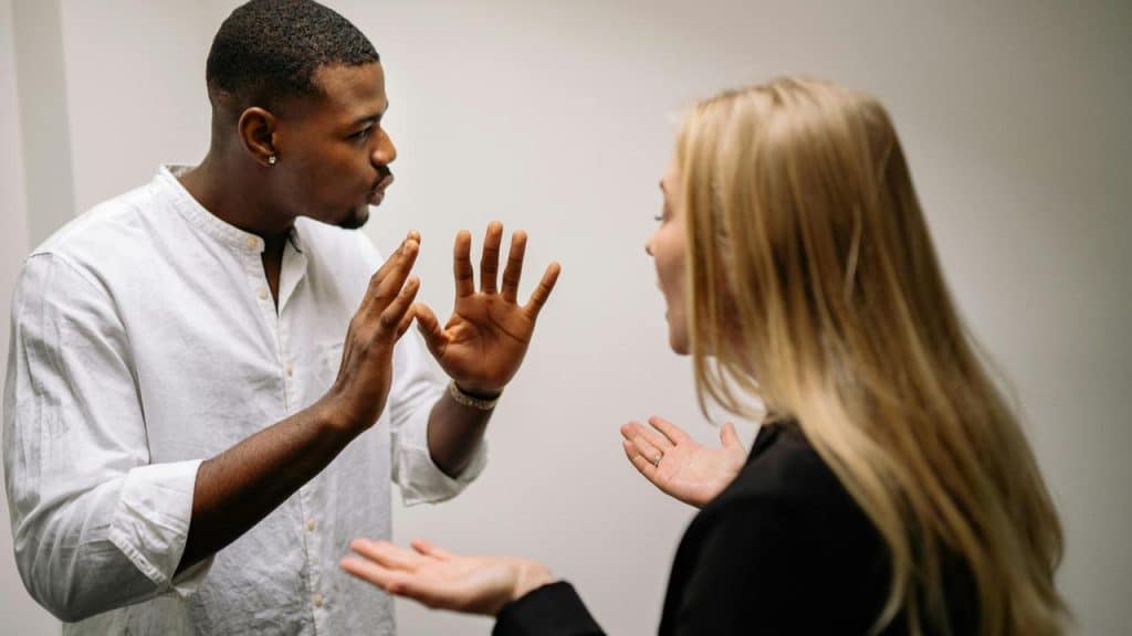 A man and a woman arguing with raised hands.