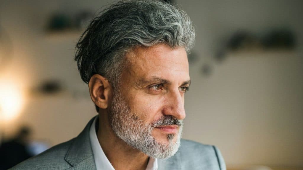 Close-up of a handsome, gray-haired man with a beard looking off to the right.