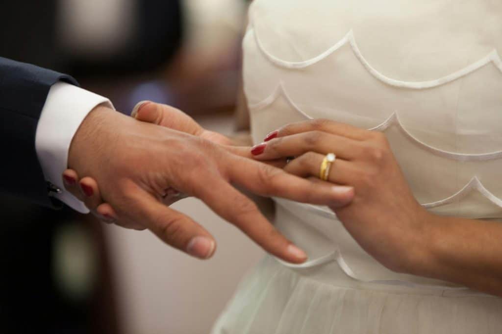 A bride putting a ring on a groom