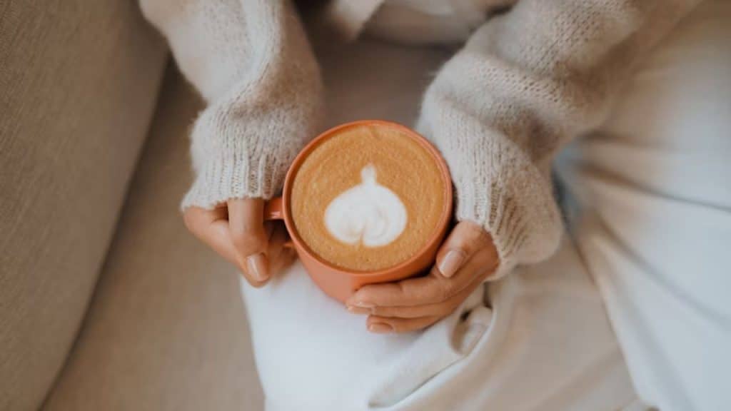 Man handing his partner a cup of coffee with a heart