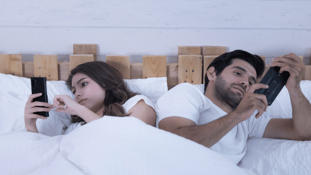 A couple using their phones in bed