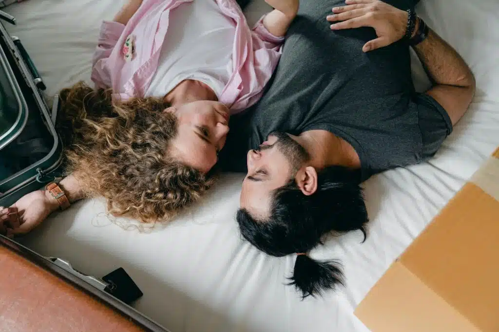 A man and woman laying at the bed