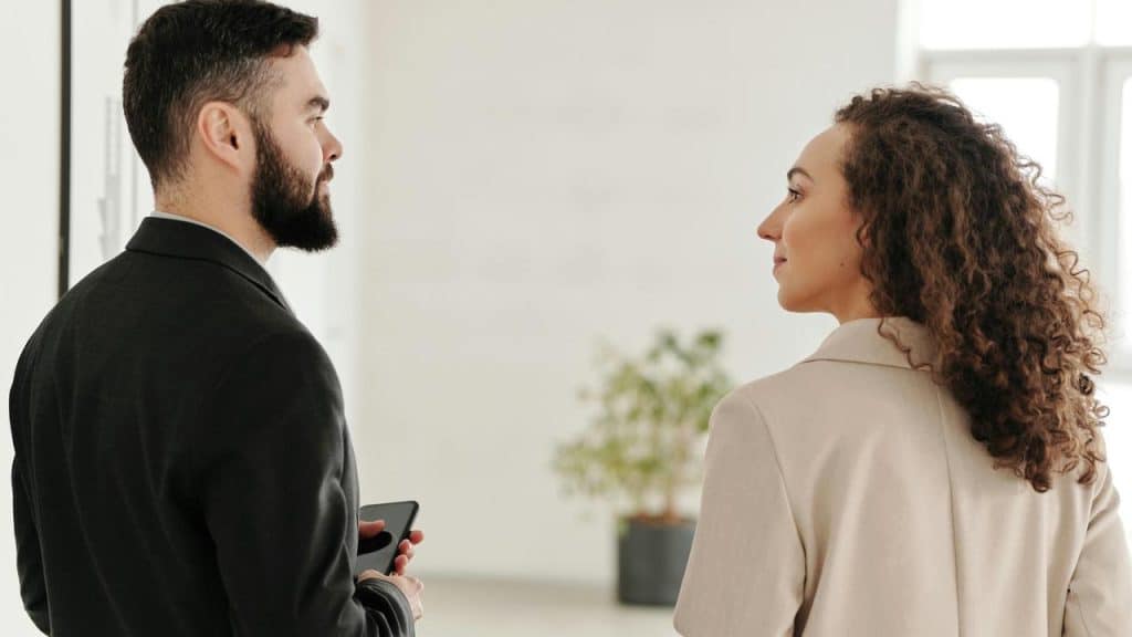 A man and a woman talking while standing indoors.