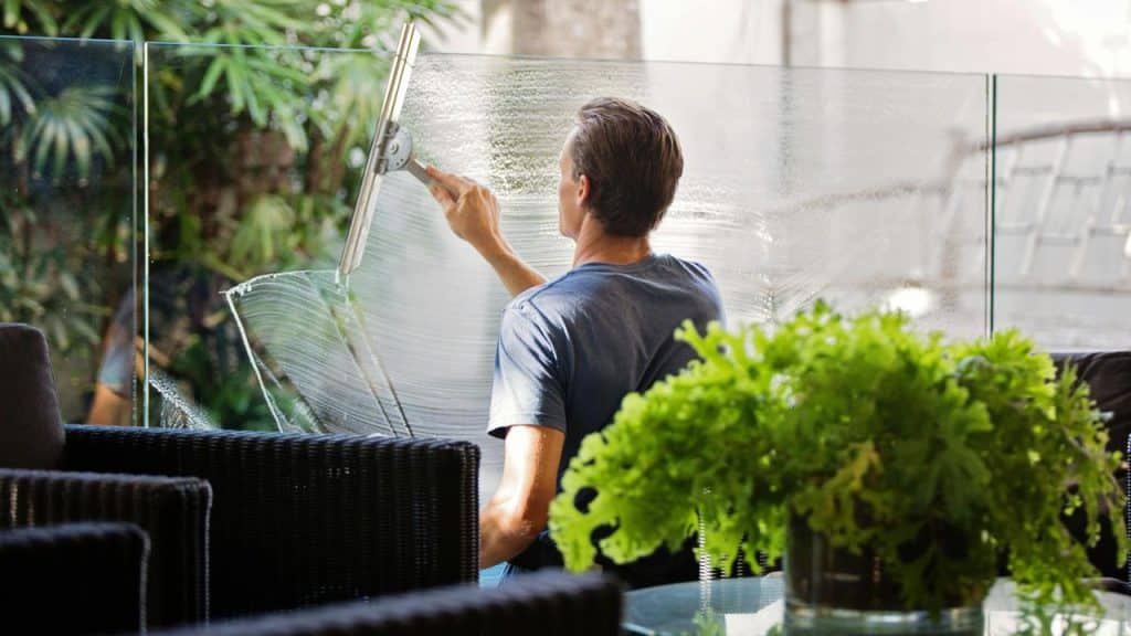 A man cleaning a glass window with a squeegee.