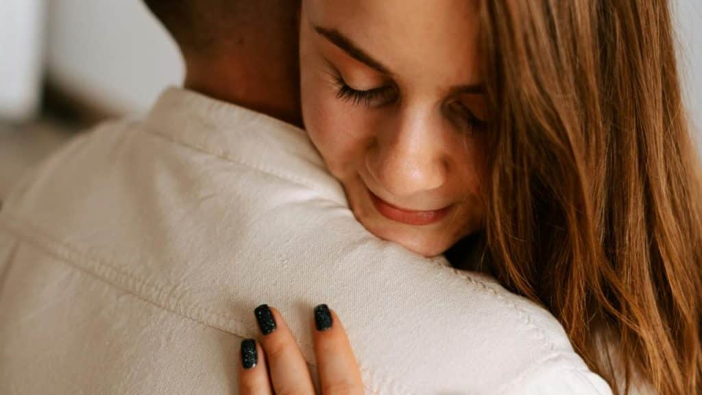 A woman hugging someone with a gentle smile.