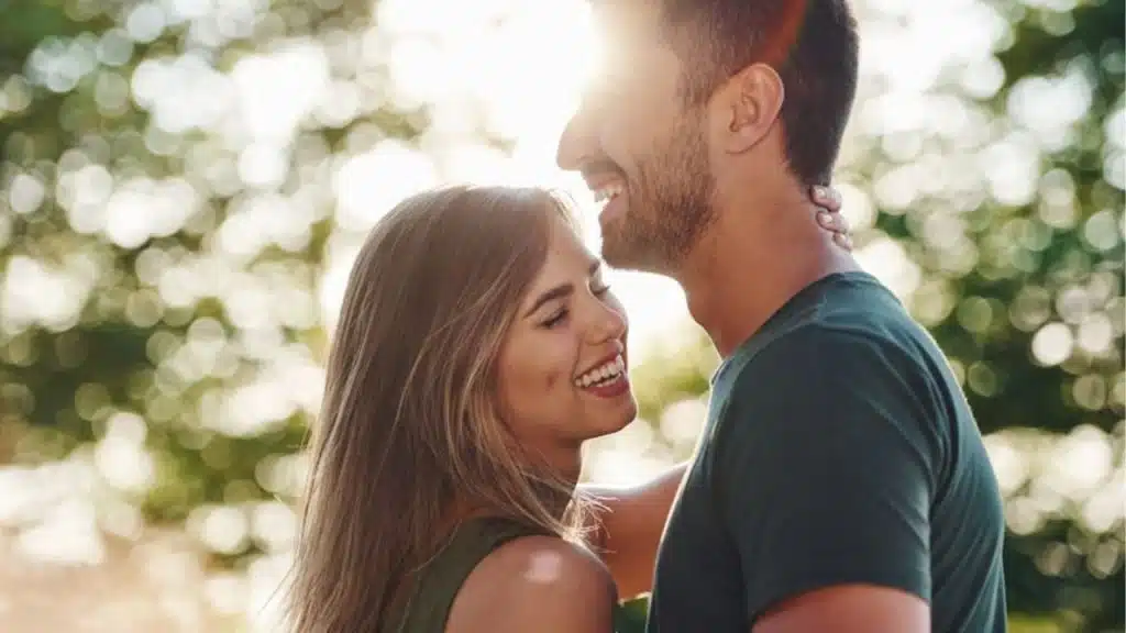 A man and a woman smiling while hugging warmly.