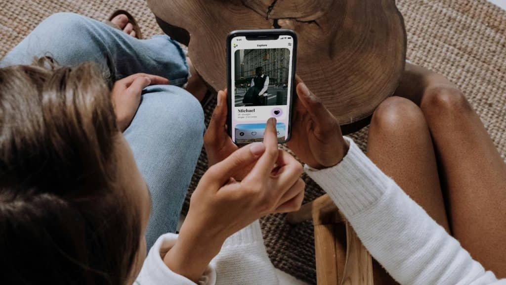 A woman using a dating app on her phone while sitting with a friend.