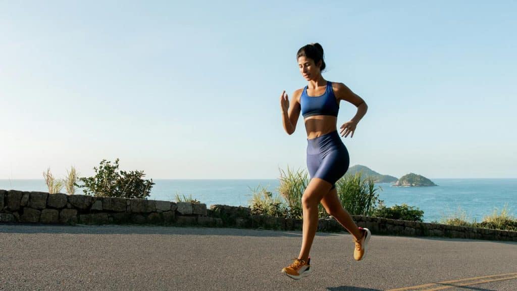 A woman jogging on a seaside road in the morning.