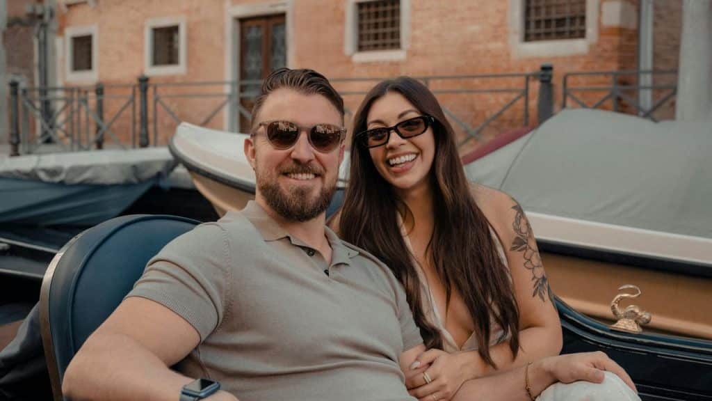 A smiling couple sitting together on a gondola in Venice.