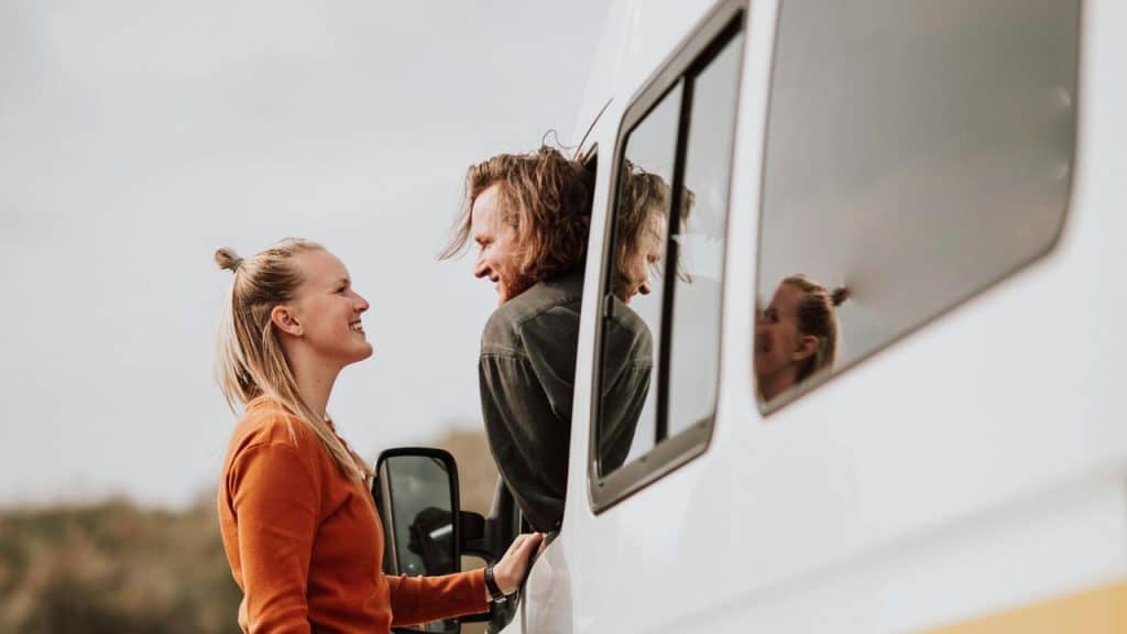 A smiling couple talking beside a white van.
