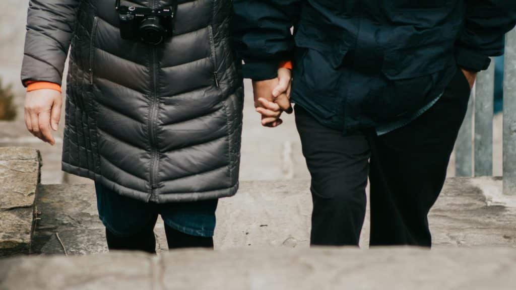 A couple holding hands while walking up stone steps.