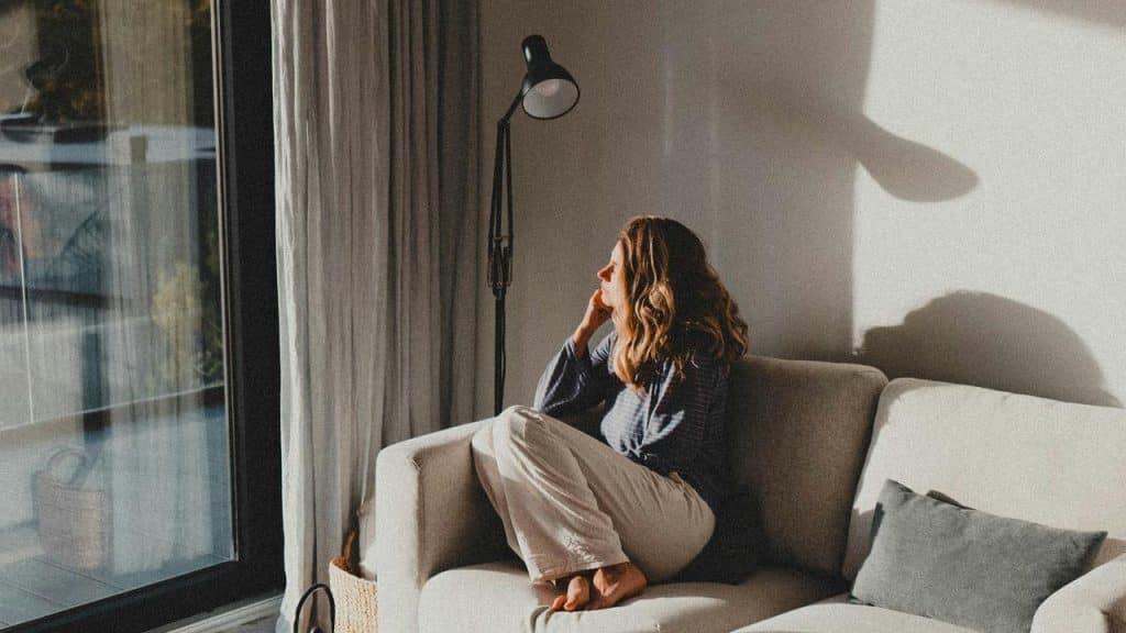 A woman sitting on a couch looking out the window.