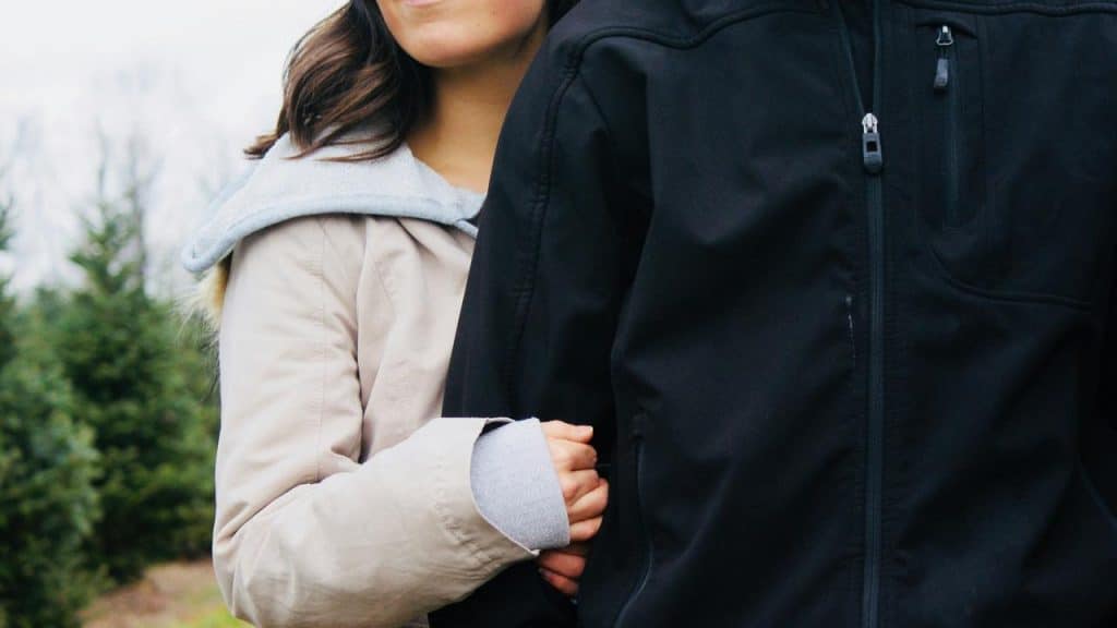 A woman holding onto a man’s arm outdoors.