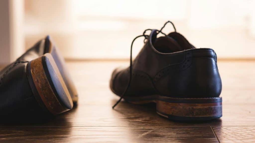 A pair of black dress shoes on a wooden floor.