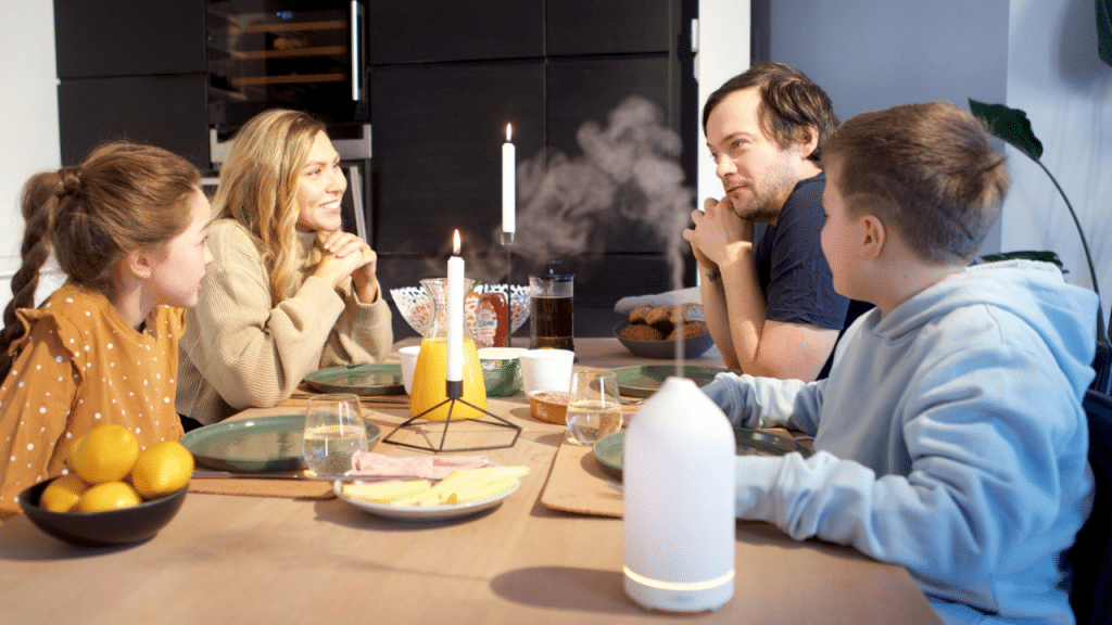 A family of four is seated around a dinner table with food and candles.