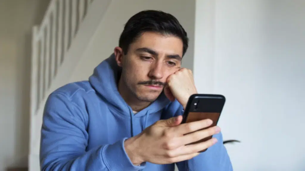 A man looking sad while texting.