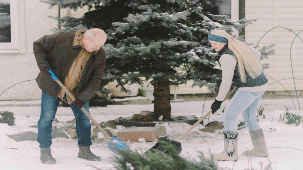 A couple shoveling snow together
