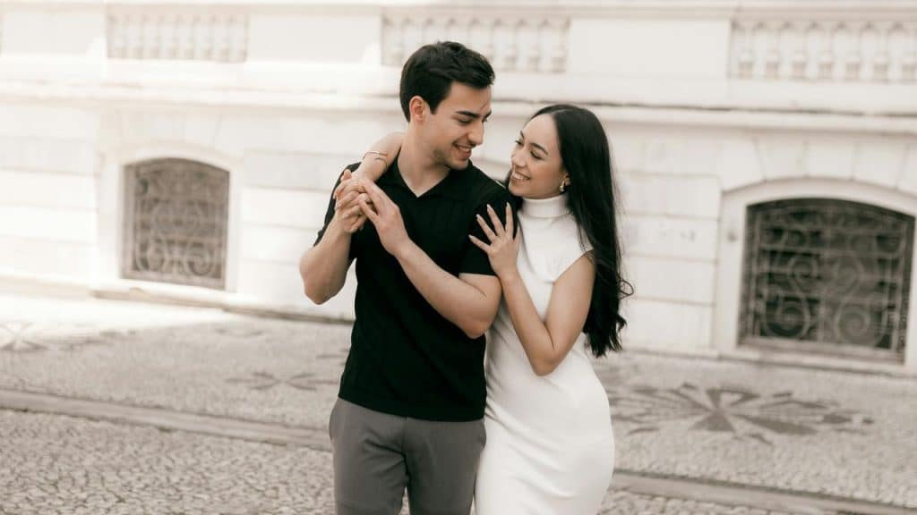 A couple walking together and smiling at each other.