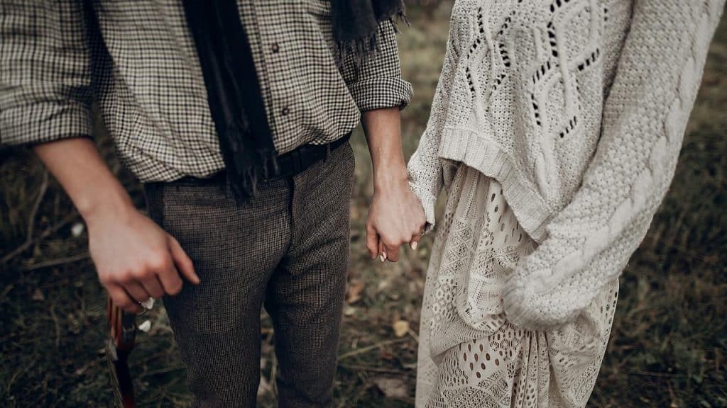 A couple holding hands while standing outdoors.